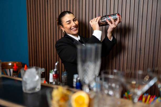 The bartender happily mixes a delicious cocktail with a cocktail shaker.