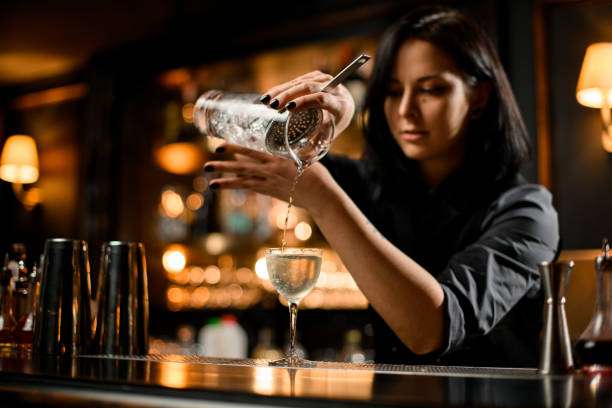 A girl mixes cocktails by herself using a cocktail shaker.