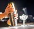 Bartender shaking a cocktail with an ornate metal Cocktail Shaker and ice-filled glass.