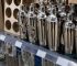 Many shiny silver cocktail shakers displayed on a store shelf, ready for purchase.