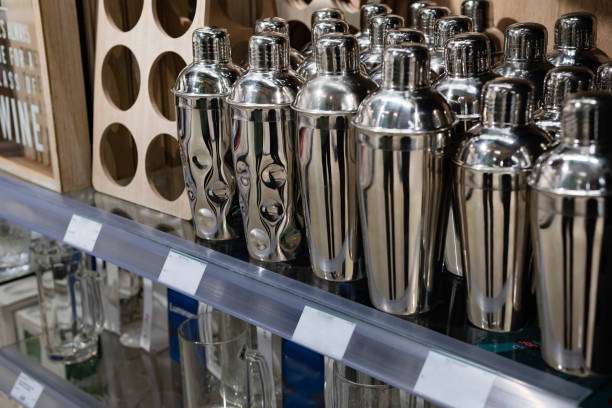 Many shiny silver cocktail shakers displayed on a store shelf, ready for purchase.