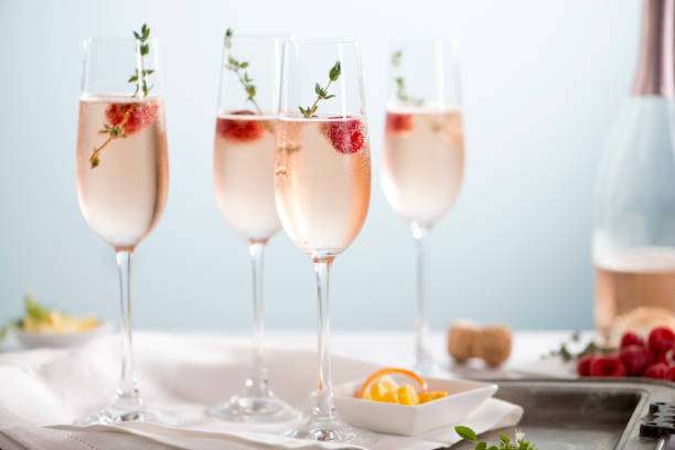 Why do bubbles form in a cocktail shaker? 2 Elegant pink sparkling cocktails with raspberries and thyme, ready to be served.