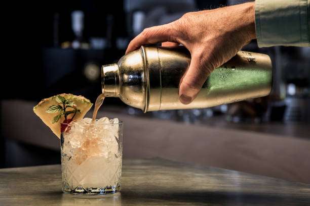 Why do bubbles form in a cocktail shaker? 3 Hand pouring a refreshing drink from a metallic cocktail shaker into an ice-filled glass.
